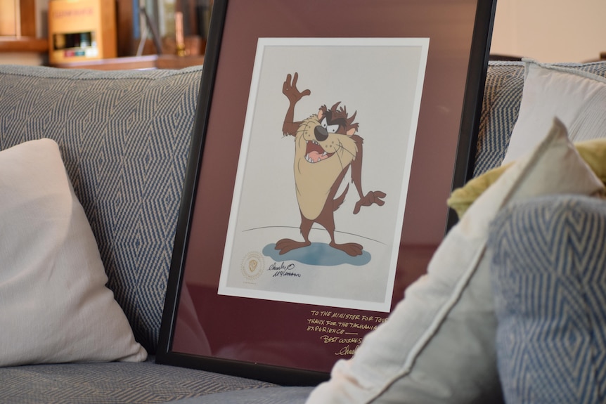Framed print of Looney Tunes character Taz, one arm raised. Image sitting on couch.