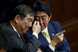 Japan's Prime Minister Shinzo Abe (R) talks with minister in charge of reviving local economies Shigeru Ishiba during the plenary session of the parliament in Tokyo July 16, 2015.