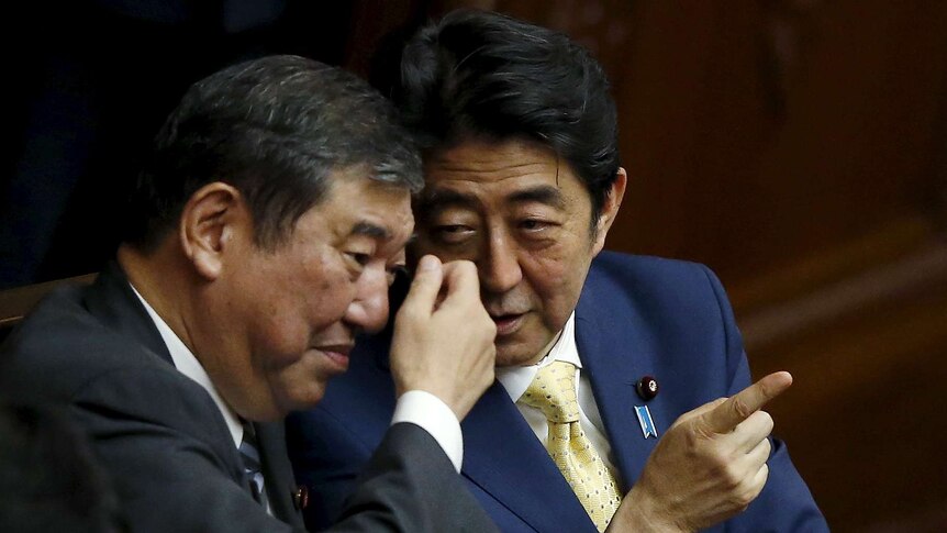 Japan's Prime Minister Shinzo Abe (R) talks with minister in charge of reviving local economies Shigeru Ishiba during the plenary session of the parliament in Tokyo July 16, 2015.