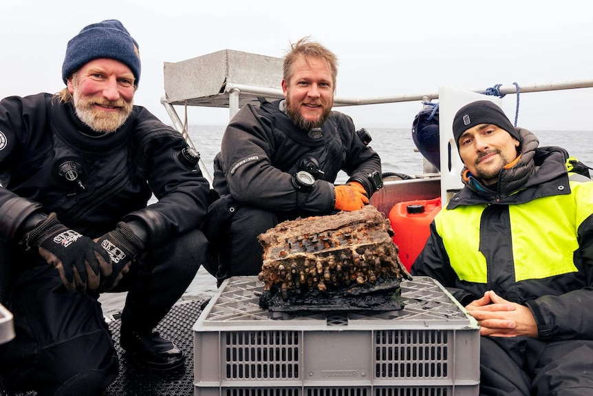 Underwater archaeologists Christian Howe (left), Florian Huber (middle) and Uli Kunz pose with a rare Enigma cipher machine.