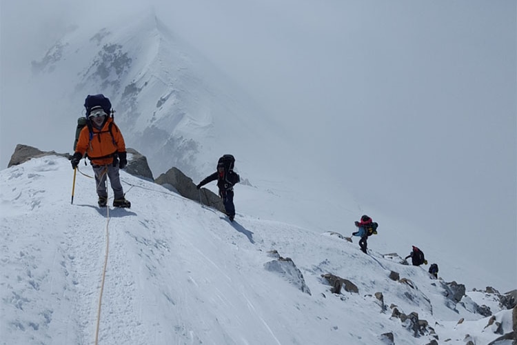 A line of four walkers roped together in deeps now on a high mountain side