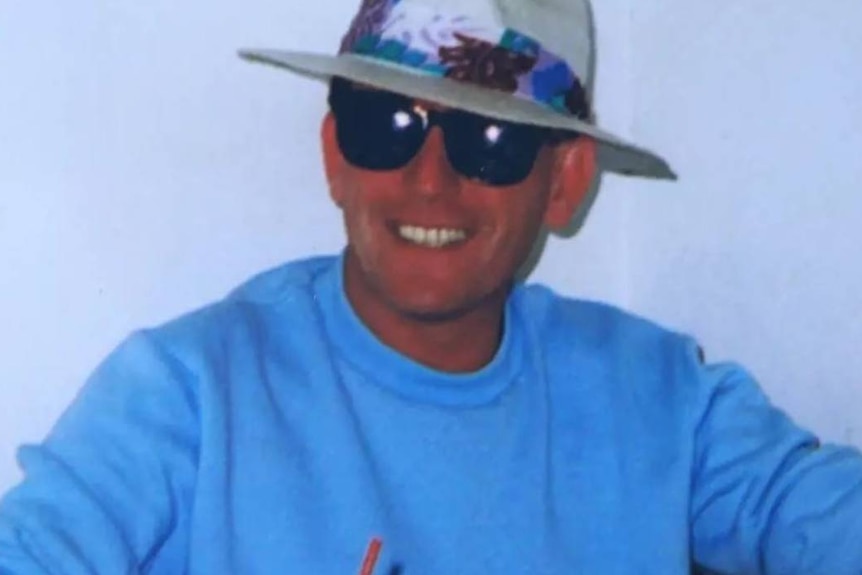 a man in sunglasses and a hat smiling at the camera