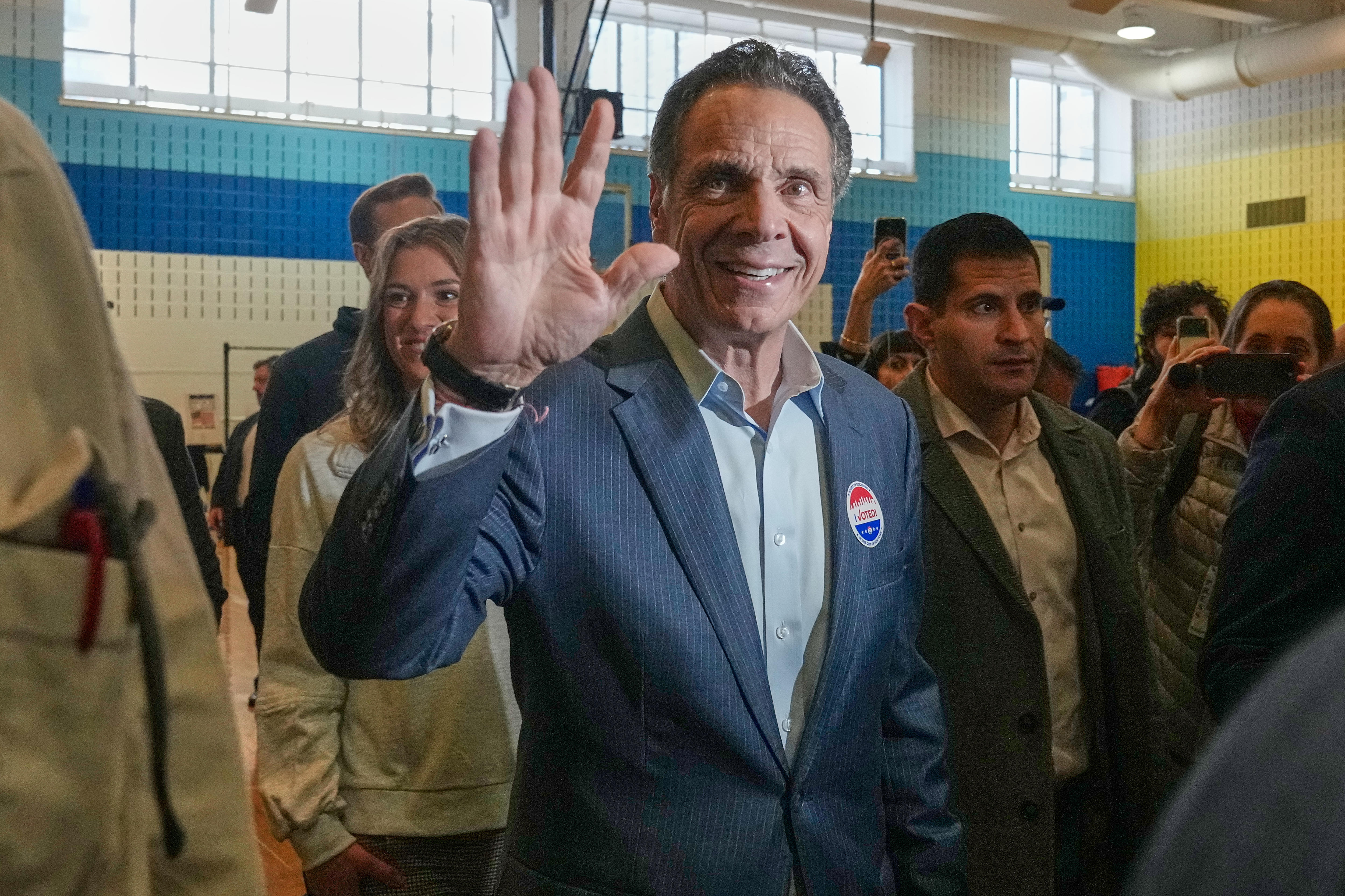 Andrew Cuomo smiling and waving in a polling station.