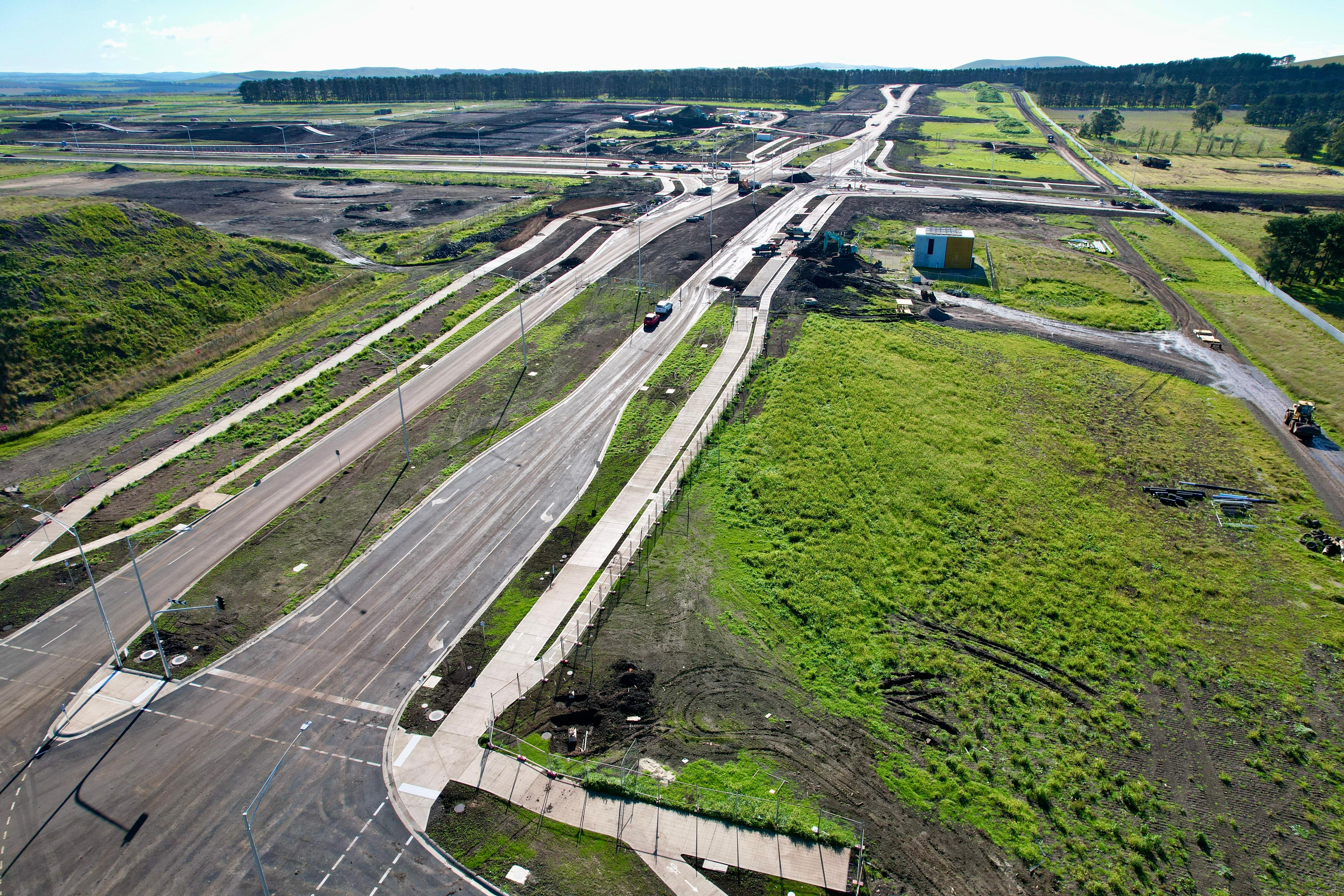 Suburban development with new dual lane road cutting across green pastures