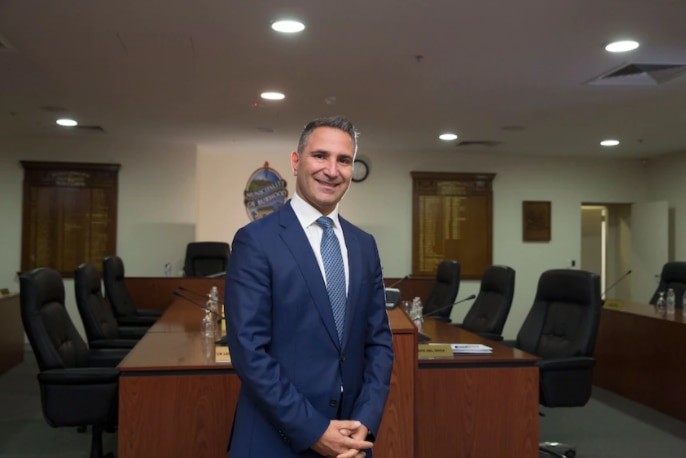 Man in suit stands in front of conference table.