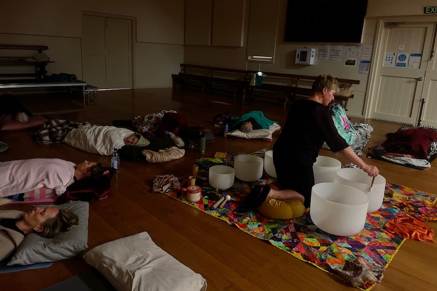 A circle of sleeping woman surround Ulrike playing the singing bowls.