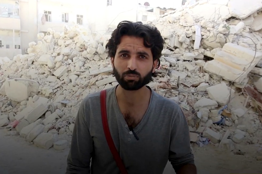 Ismail al-Abdullah stands in front of the ruins of a building in Aleppo.