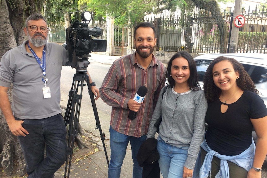 four people part of the team posing with a camera.