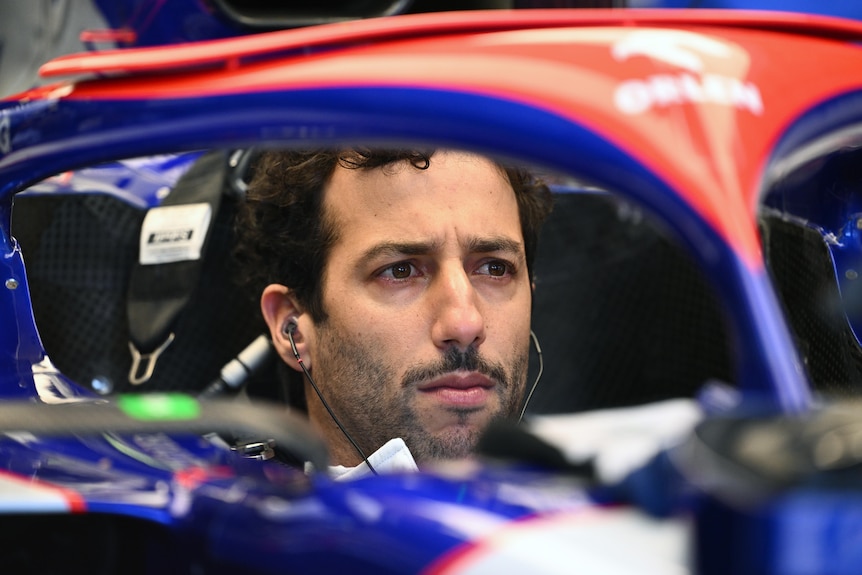 Daniel Ricciardo sitting in his RB, with no helmet, preparing to drive