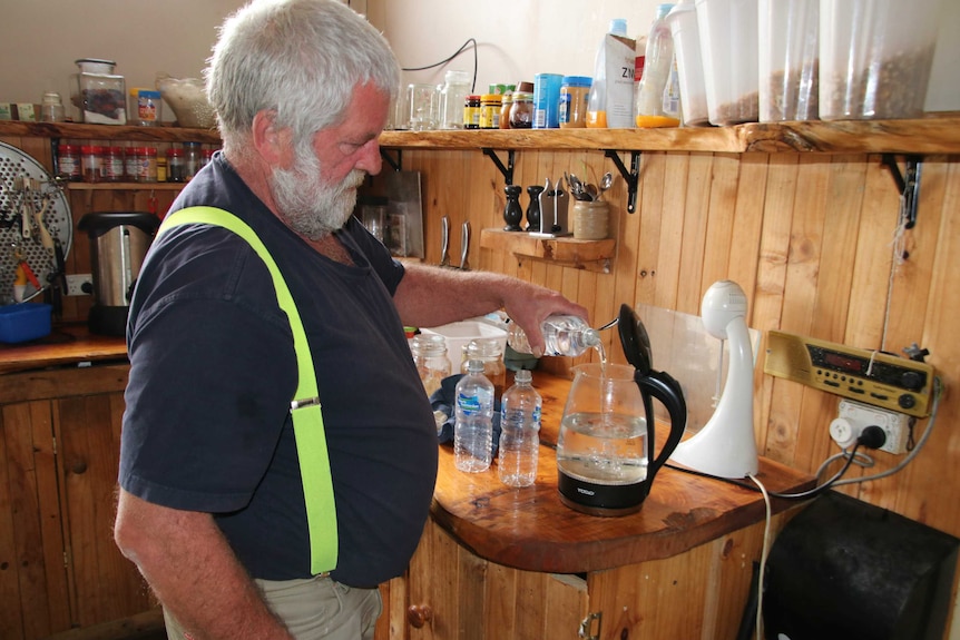 Pioneer resident Mark Simpson pouring bottled water into his kettle for a cuppa