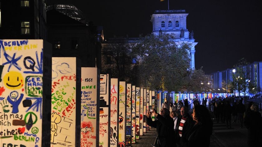 People look at the individually painted dominos along the former route of the Berlin wall
