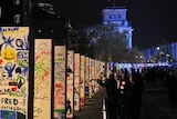 People look at the individually painted dominos along the former route of the Berlin wall