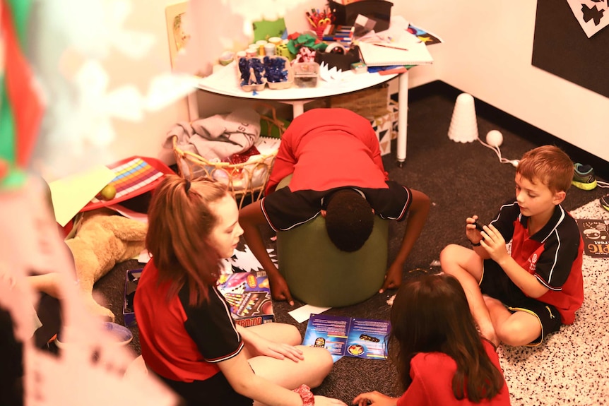 Students play amid a small room full of arts and crafts material.