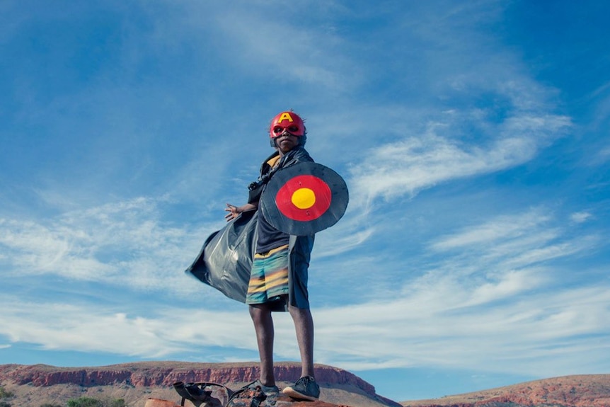 a young aboriginal superhero standing on rock