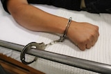 A patient is handcuffed to a hospital bed.