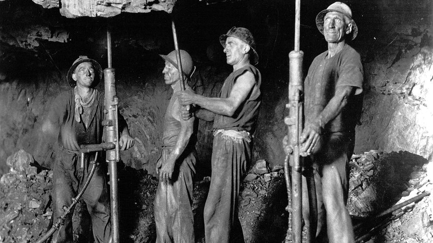 Black and white photo of four Mount Isa miners stope drilling in the 1930s.