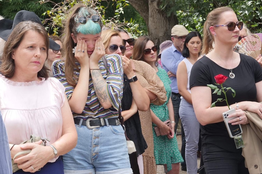 A woman cries in crowd at a Red Rose rally against domestic violence outside Parliament House in Brisbane.