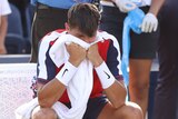 Tennis player sitting with his hands on his face looking disappointed after losing a match