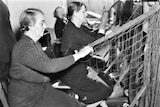 A black and white photograph of two older women sitting assembling a large net.