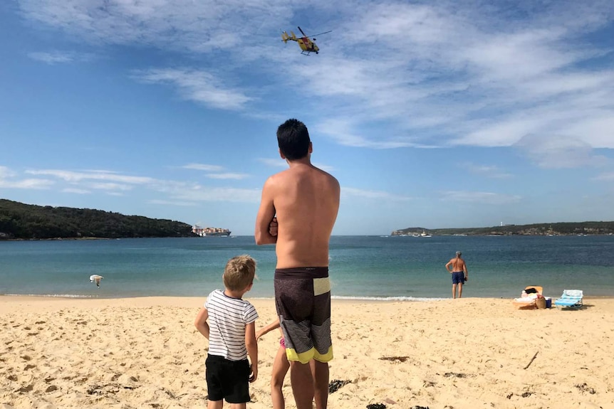 A man and a young boy facing the ocean.