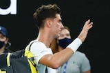 Thanasi Kokkinakis waves to the crowd as he leaves the court at the Australian Open. Stefanos Tsitsipas is seated and applauding