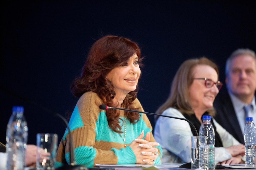 Cristina Fernandez de Kirchner sitting with two people to her right
