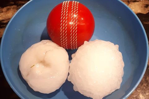 Two hailstones sitting in a bowl with a cricket ball.