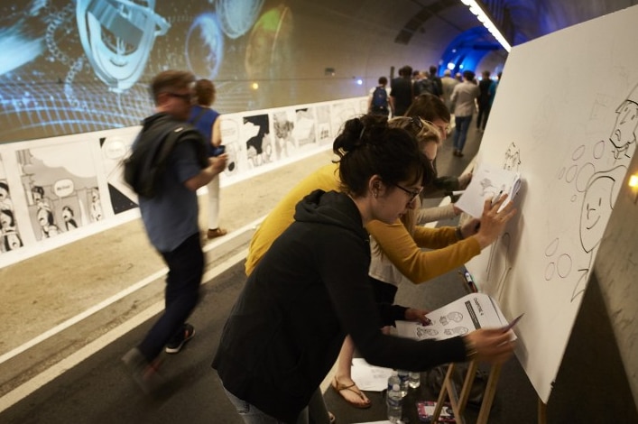 People draw along comic strip displayed along tunnel in Lyon
