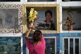 A woman puts flowers in a columbarium box to honour her dead aunt.