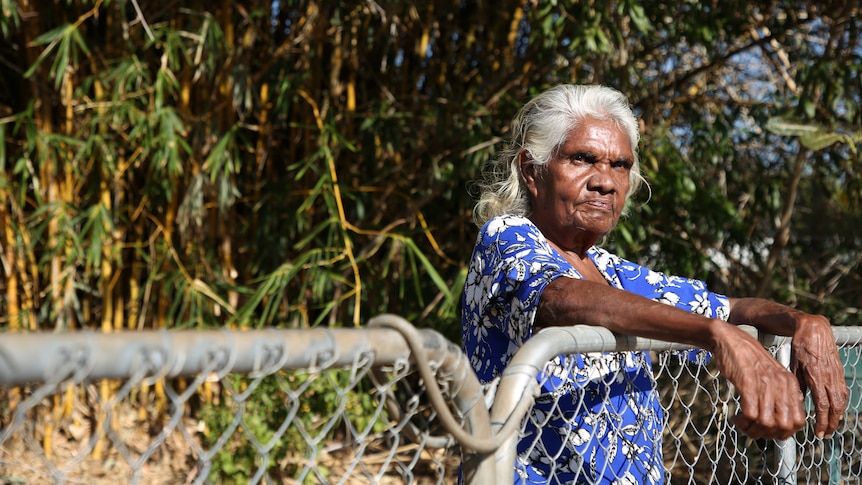 Indigenous woman Helen Fejo-Frith leans against a fence in the front yard of her home.