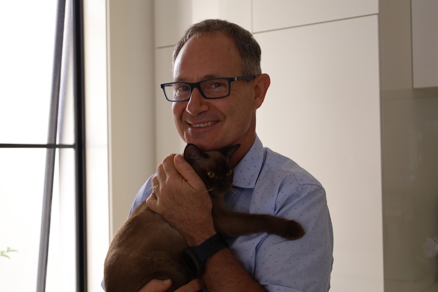 Dr Nylander smiles as he holds his cat.