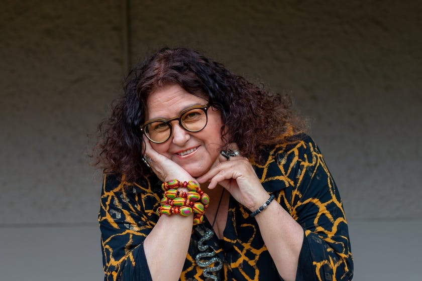 A woman with long curly hair smiling resting on hand