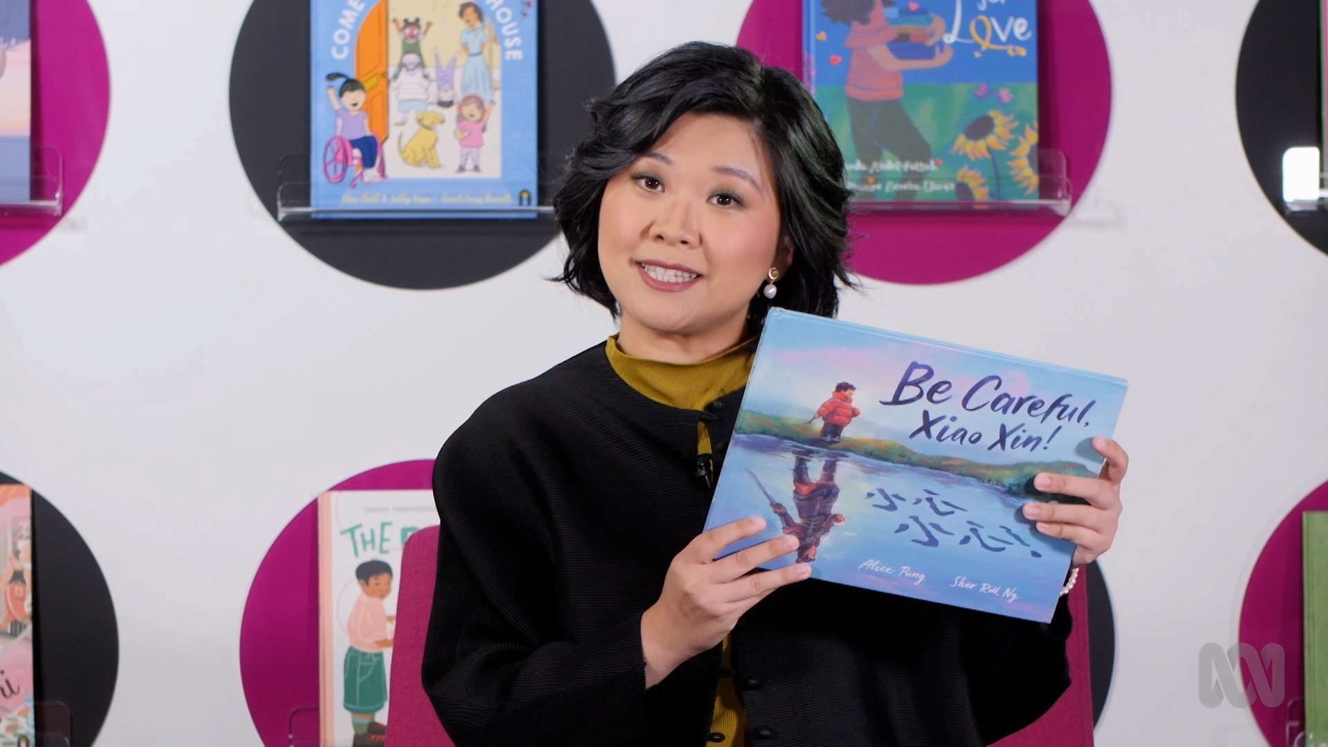 Teacher FangNi Zhou holds up story book, Be Careful, Xiao Xing!
