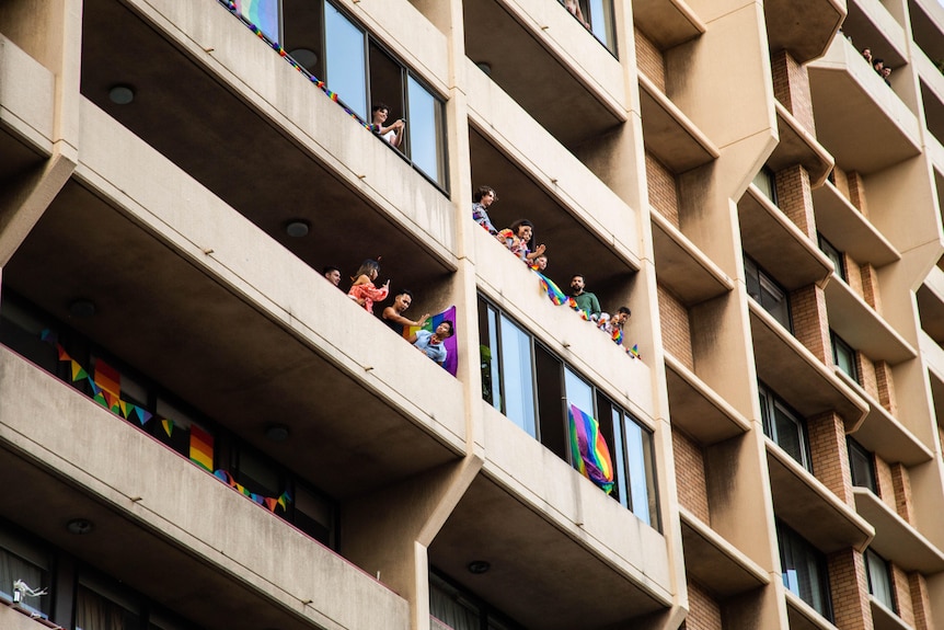 Les gens se pressent sur les balcons décorés de drapeaux arc-en-ciel au-dessus du photographe