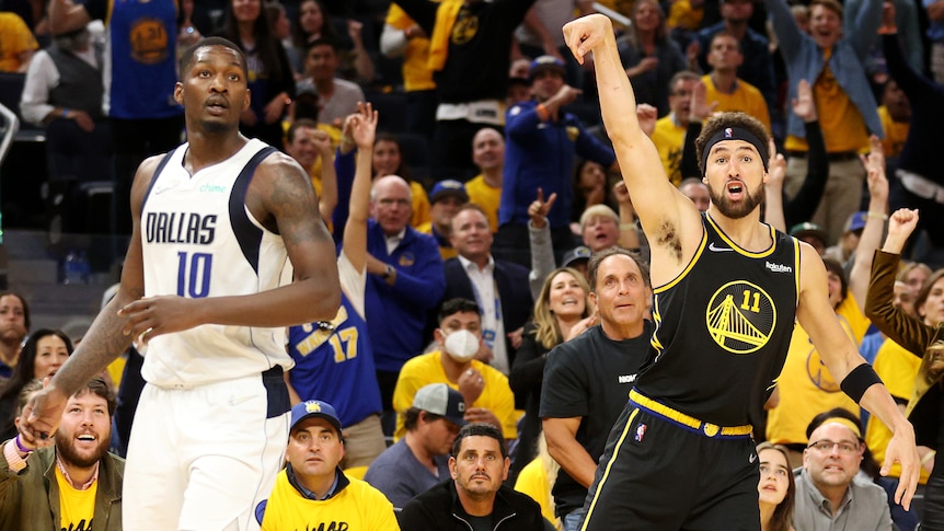 A Golden State Warriors NBA player celebrates scoring a basket against the Dallas Mavericks.