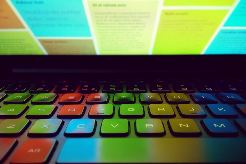 A colourful computer screen reflects on a keyboard.