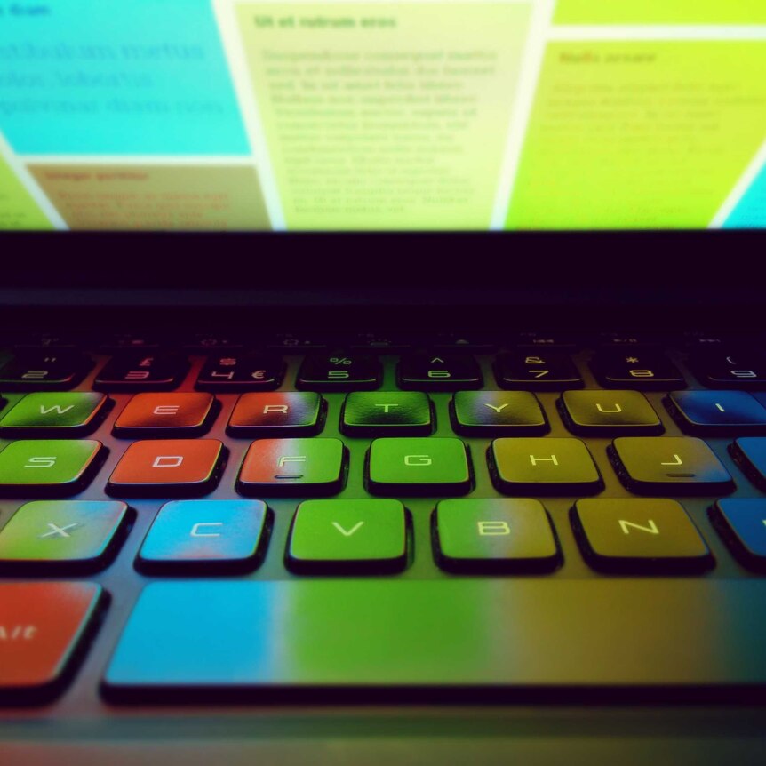 A colourful computer screen reflects on a keyboard.