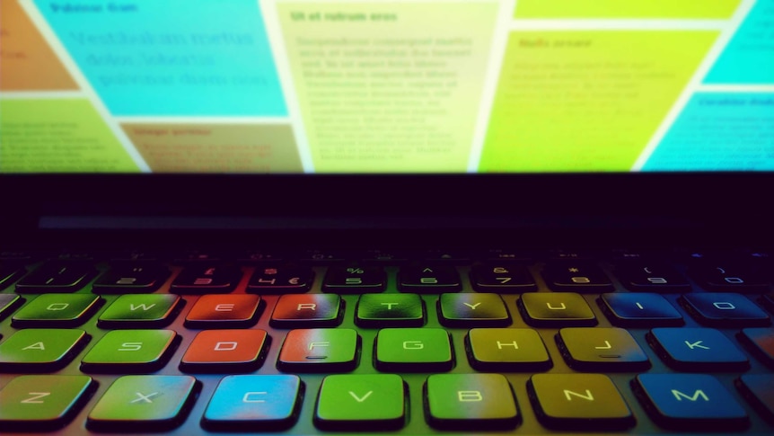 A colourful computer screen reflects on a keyboard.