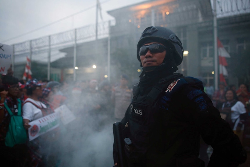 A police officer standing in front of a protest at the prison holding Ahok.