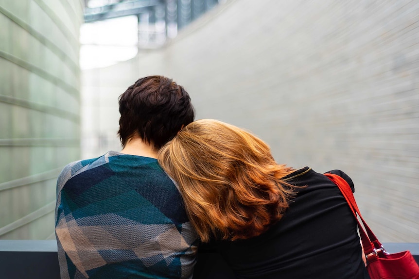 Back of two women's heads, with one resting on the other's shoulder