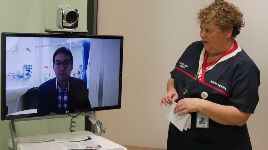 Nurse standing next to a TV screen with specialist on video link