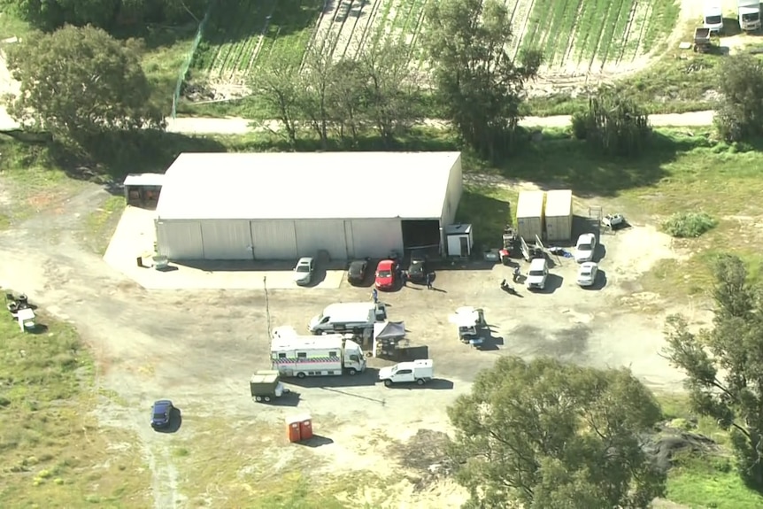 An aerial image of police at a semi-rural property near a large warehouse
