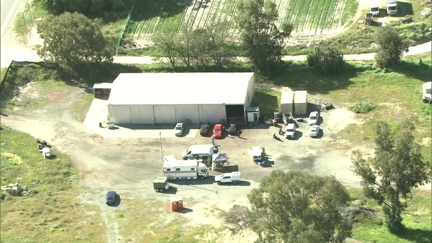 An aerial image of police at a semi-rural property near a large warehouse