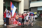 A woman carrying a Serbian flag leads a group of protestors.