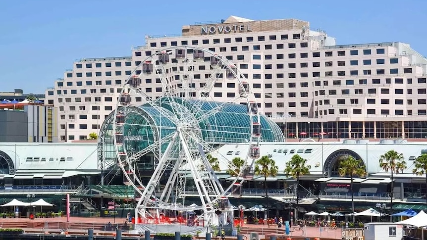 a hotel behind a ferris wheel by a city harbour