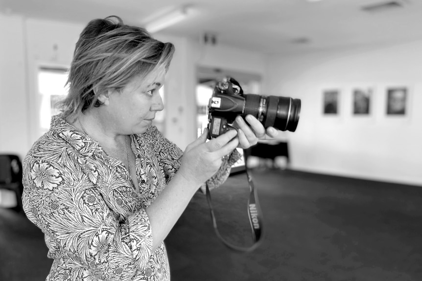 A woman looks through the lens of a camera
