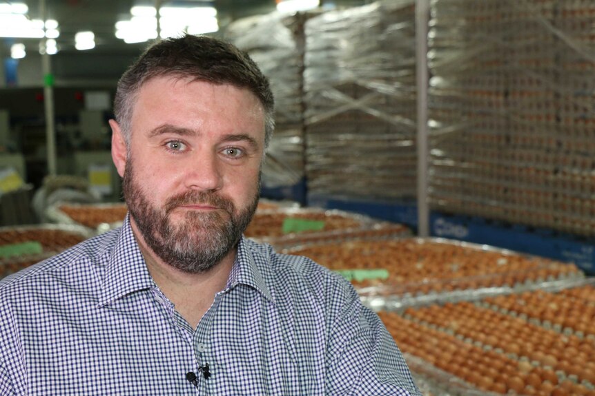 close-up of Egg Farmers Australia chief executive John Dunn as he stands in front of a crate with hundreds of eggs.