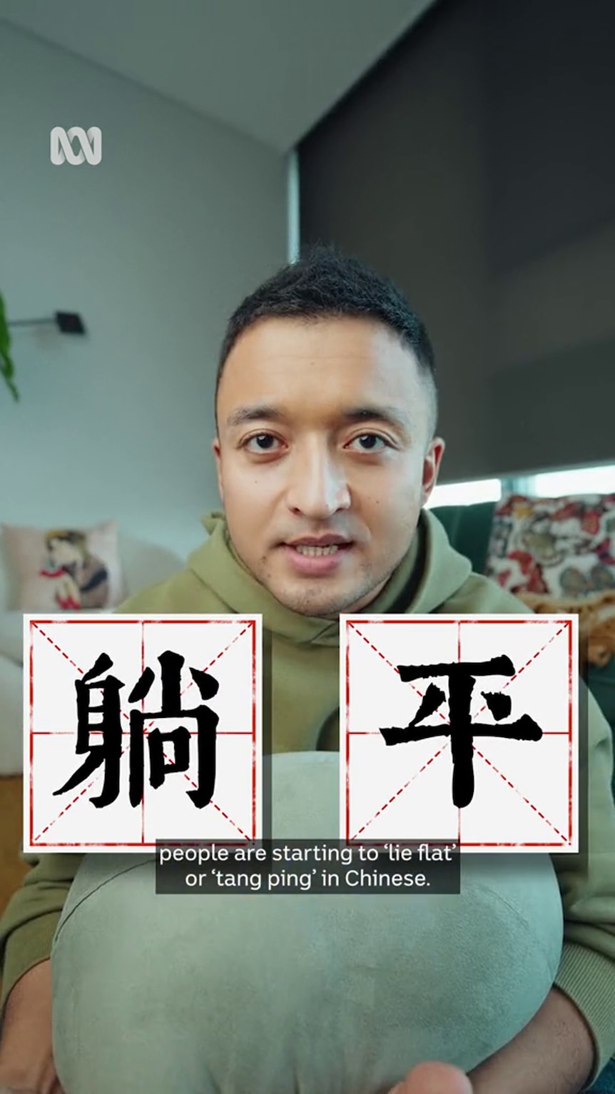 A young Asian man with short hair looks down the lens with two Chinese characters superimposed in front of him