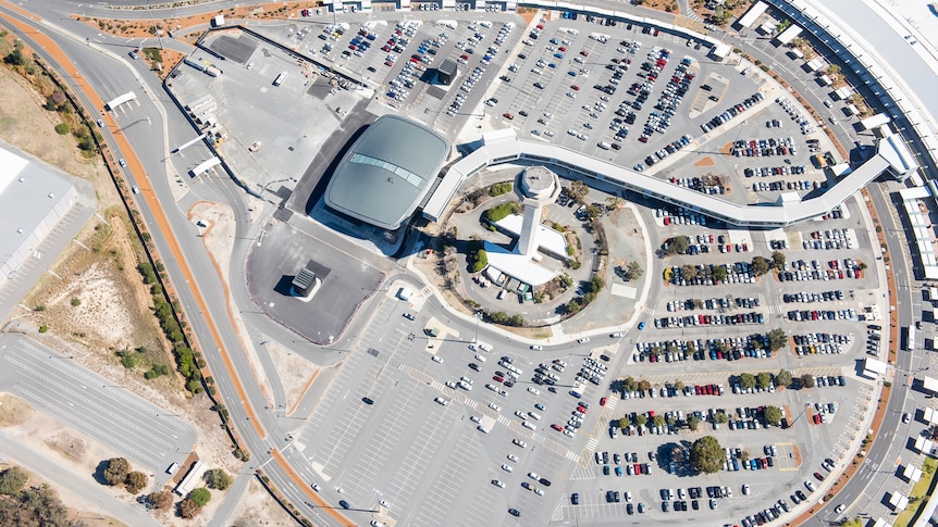 A view from above a large carpark with a tall white building in the middle.