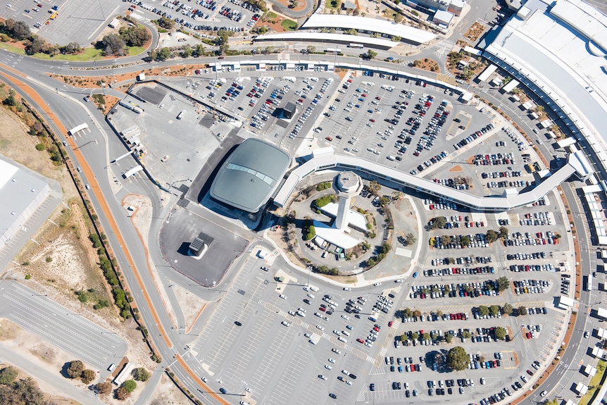 A view from above a large carpark with a tall white building in the middle.